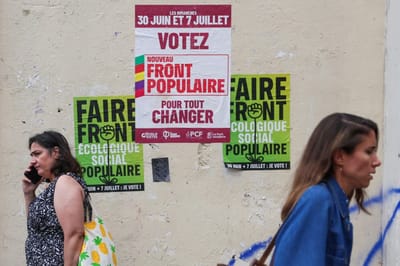Two pedestrians walk past election posters of the left-wing "Nouveau Front Populaire" (New Popular Front – NFP) in Paris, on July 3, 2024, ahead of the second round of France's legislative elections. (Photo by EMMANUEL DUNAND / AFP)