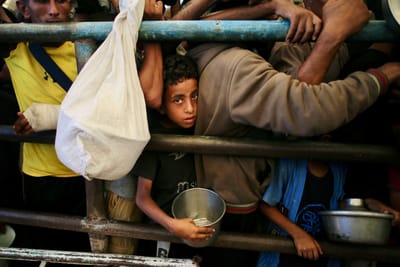 Un niño en Gaza haciendo fila para recibir comida en una multitud.