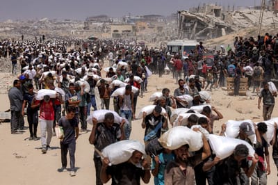 Varias personas caminan con sacos de harina entregados después de que camiones con ayuda humanitaria entraran en el norte de Gaza el 27 de julio de 2025 procedentes del paso fronterizo de Zikim.
