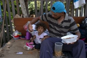 (FILES) In this file photo taken on August 23, 2018 a Venezuelan man and his daughter eat a meal on the side of a road in Boa Vista, Roraima state, Brazil. / AFP PHOTO / Mauro Pimentel