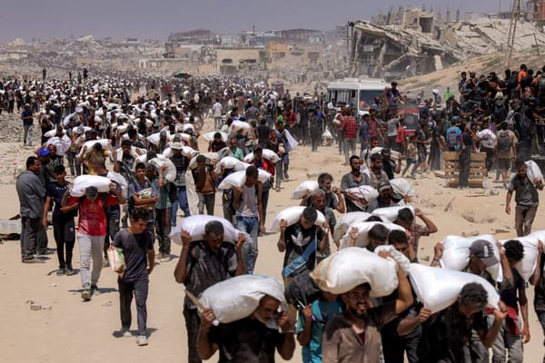 Varias personas caminan con sacos de harina entregados después de que camiones con ayuda humanitaria entraran en el norte de Gaza el 27 de julio de 2025 procedentes del paso fronterizo de Zikim.